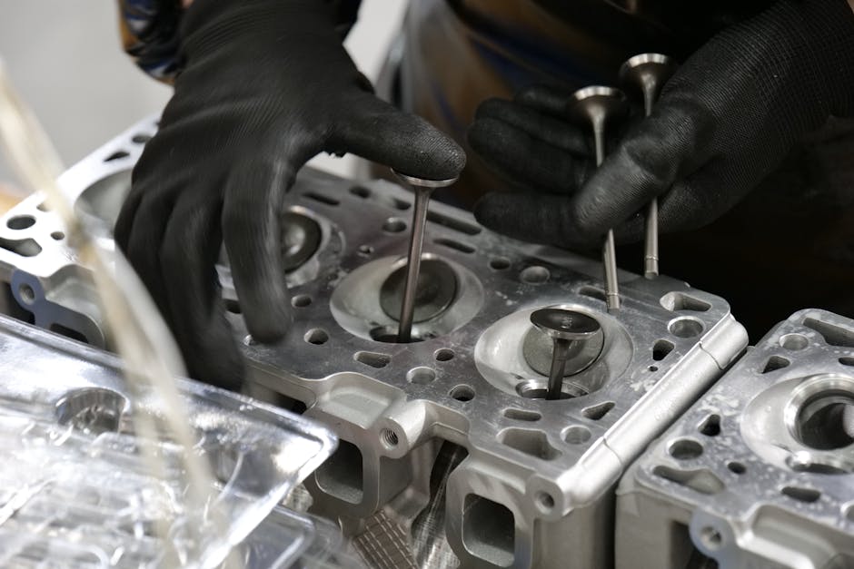 Close-up of mechanic's hands working on engine cylinder head assembly with valves.