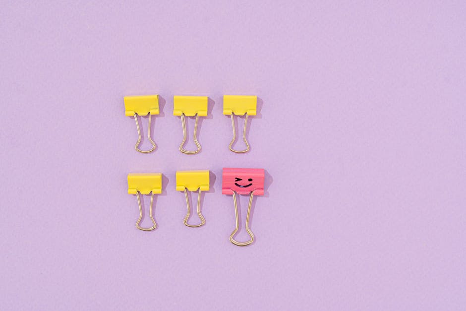 Yellow and pink binder clips arranged on a purple surface in a playful layout.