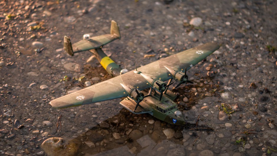 Close-up of a vintage military aircraft model resting on river stones, depicting historical army aviation.