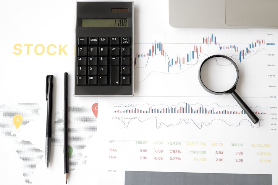 Flat lay of stock market analysis tools including calculator, graphs, and magnifying glass.