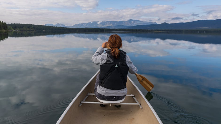 A woman enjoys a peaceful canoe ride on Kinaskan Lake with scenic mountain views.