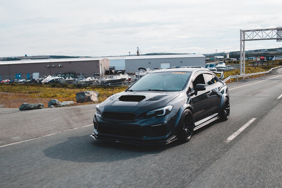Expensive black tuned sports car with glossy surface and big front body kit riding on paved road out of city in daylight