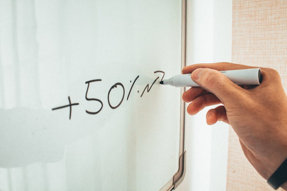 Close-up of a hand writing '+50%' on a whiteboard, conveying education or business concepts.