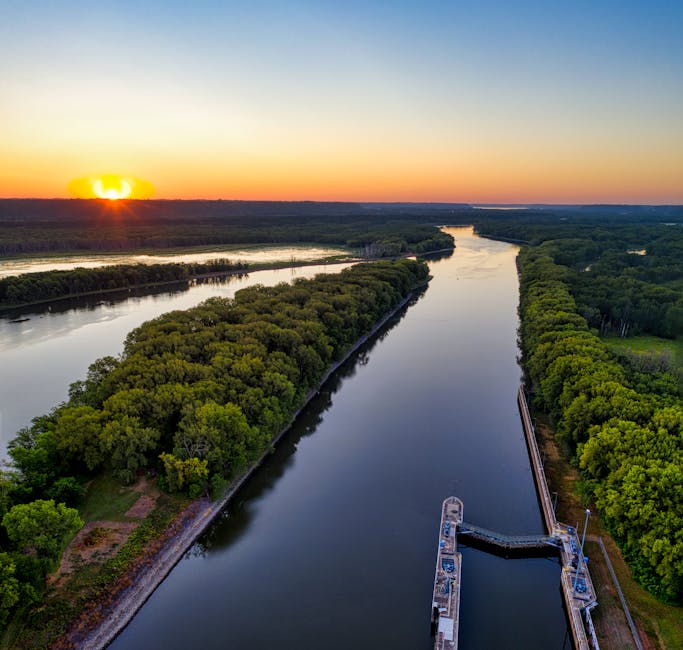 A drone captures a serene water canal surrounded by lush trees at sunset in Welch, Minnesota.