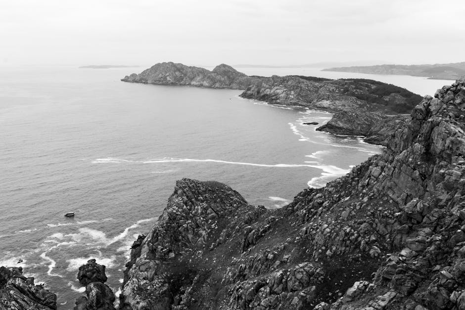 Monochrome aerial shot of Galician islands, showcasing rugged cliffs and the Atlantic Ocean.