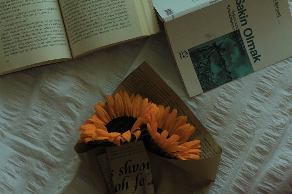 A serene still life of sunflowers and books on a soft fabric surface.