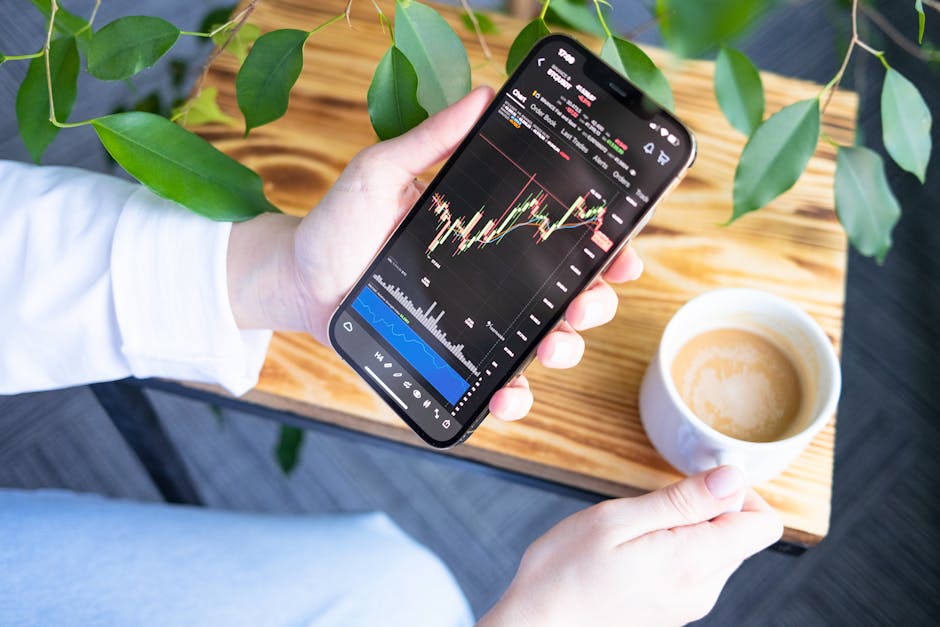 Woman holding smartphone showing stock market graph while enjoying a cup of coffee.