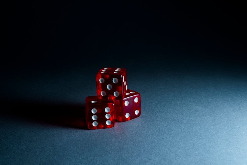 Three red transparent dice stacked on a dark surface, highlighting their reflective surfaces and dots.