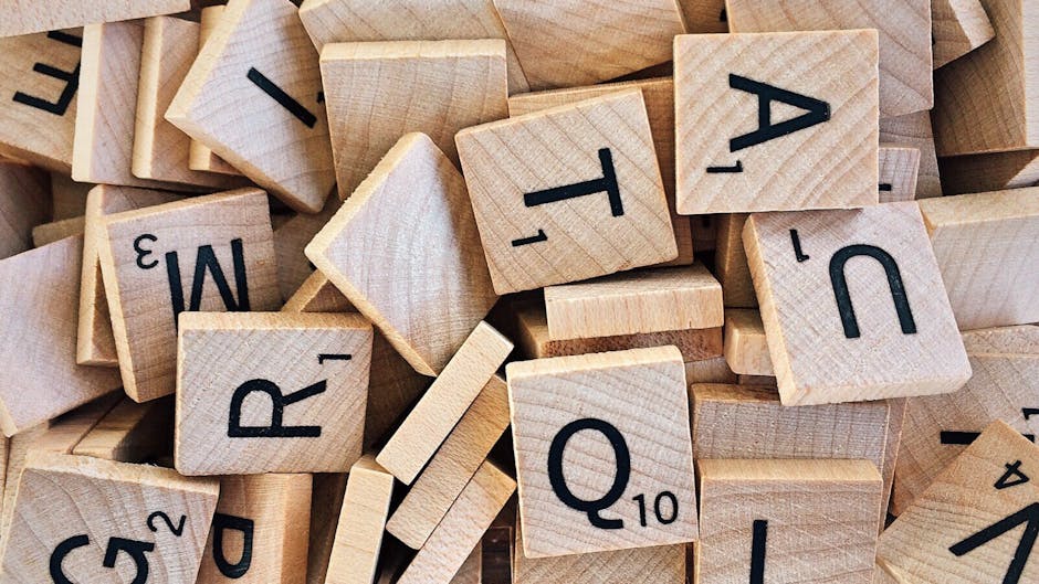 Pile of wooden Scrabble tiles showcasing various letters and numbers.