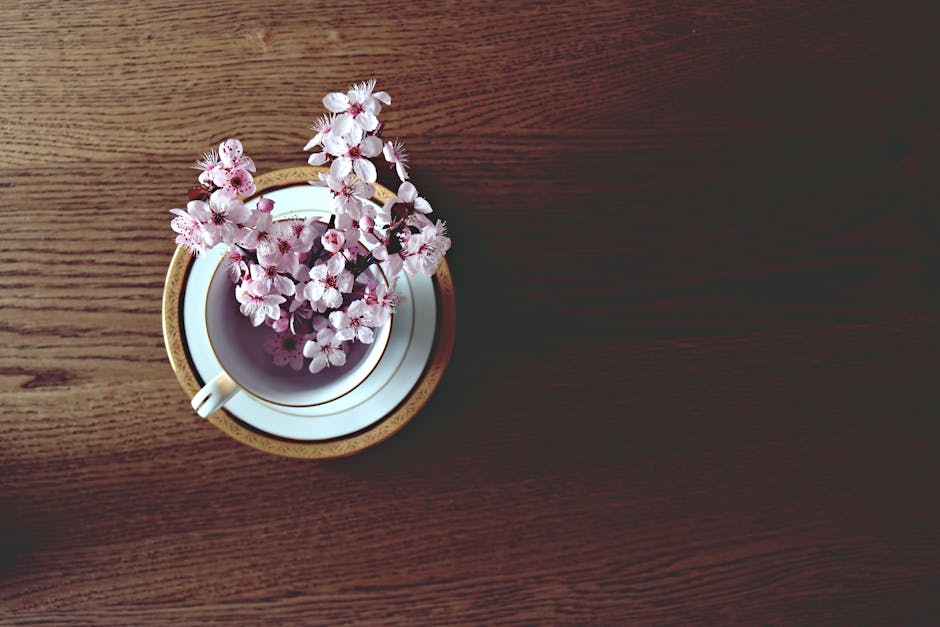 Aesthetic arrangement of cherry blossoms in a teacup on a wooden table. Perfect for spring themes.