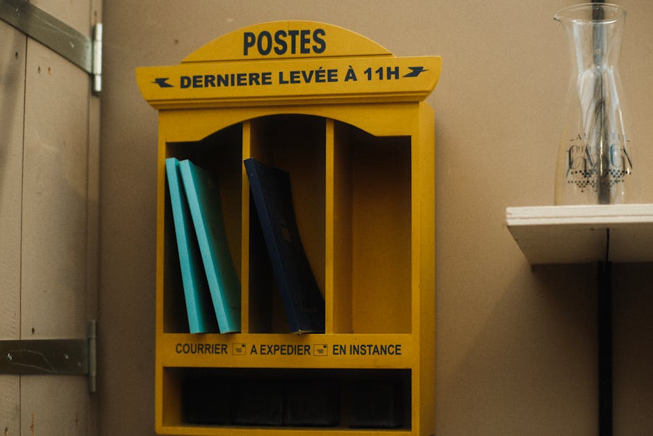 Vintage yellow postal shelf with books and a glass vase in an indoor setting.