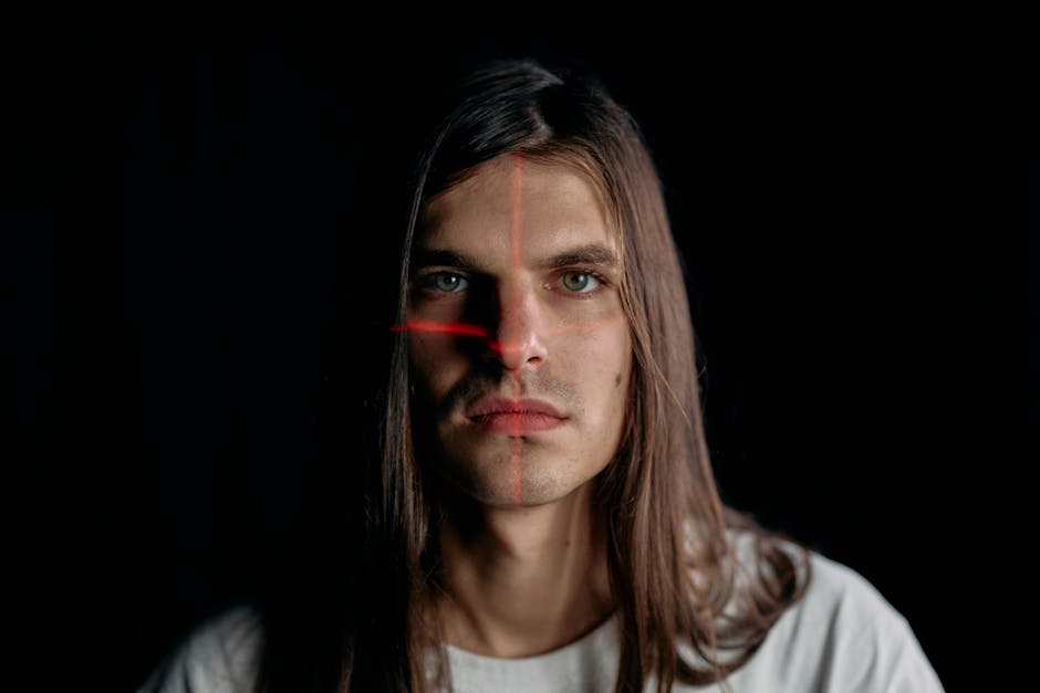 Studio portrait of a man with long hair featuring a facial recognition laser grid.