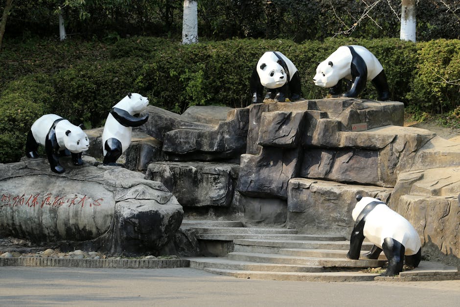 Panda statues on rock formations amidst greenery, daytime outdoors.