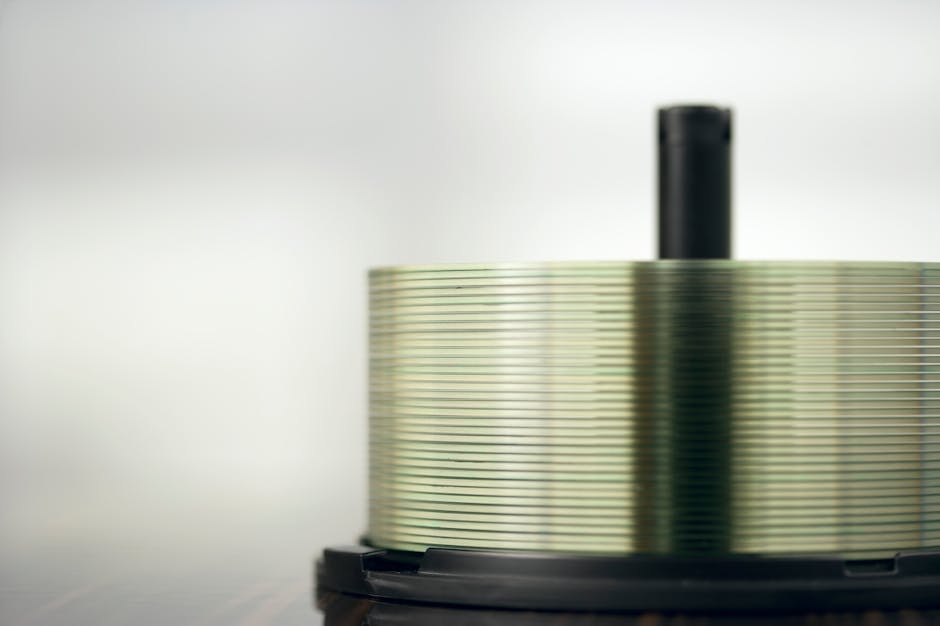 Detailed view of a stack of compact discs on a spindle, highlighting their reflective surfaces.