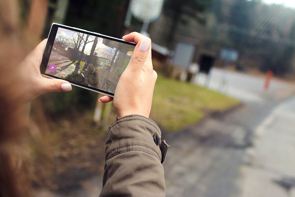 Woman capturing outdoor scenery using a smartphone. Close-up of hands holding the device.