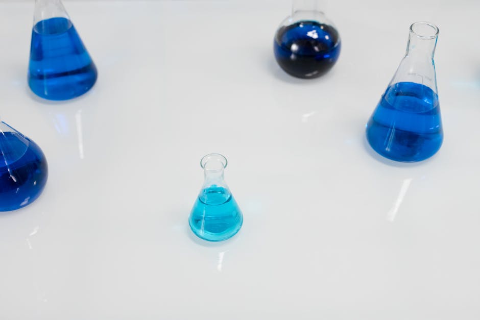 Various glass flasks filled with blue liquid in a scientific setting, perfect for research themes.