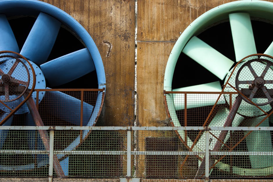 Close-up of large industrial ventilators mounted on an aging building exterior.