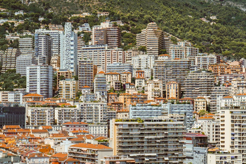 Vibrant urban skyline of Monaco with modern high-rise buildings against a lush green backdrop.