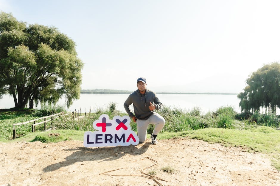 A man kneeling by a sign and lake in Lerma, Mexico, showing summertime vibes and serenity.