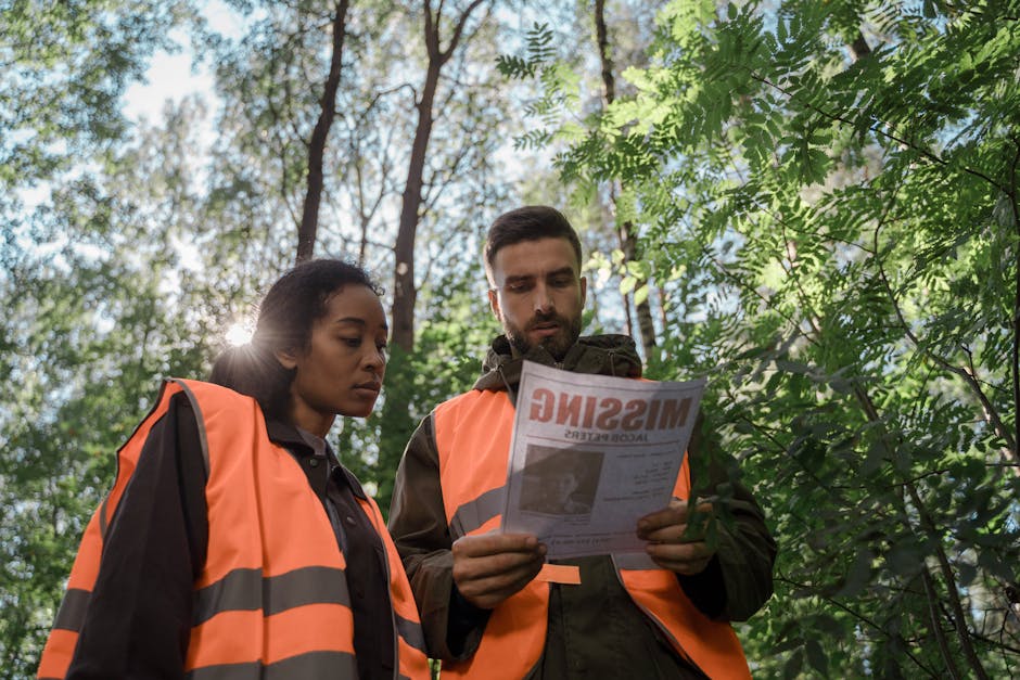 Team members in safety vests examine a missing person flyer in a forest setting.