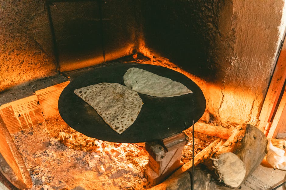 Authentic Turkish flatbreads baking on a hot iron plate over an open fire in a rustic setting.