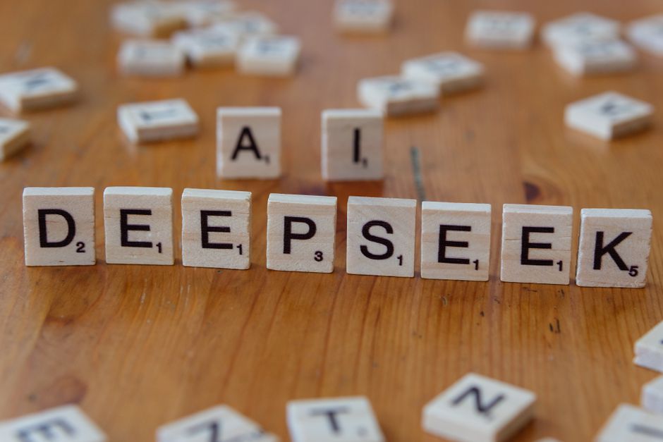 Wooden Scrabble tiles spelling 'DEEPSEEK' with 'AI' on a wooden table, illustrating AI concepts creatively.