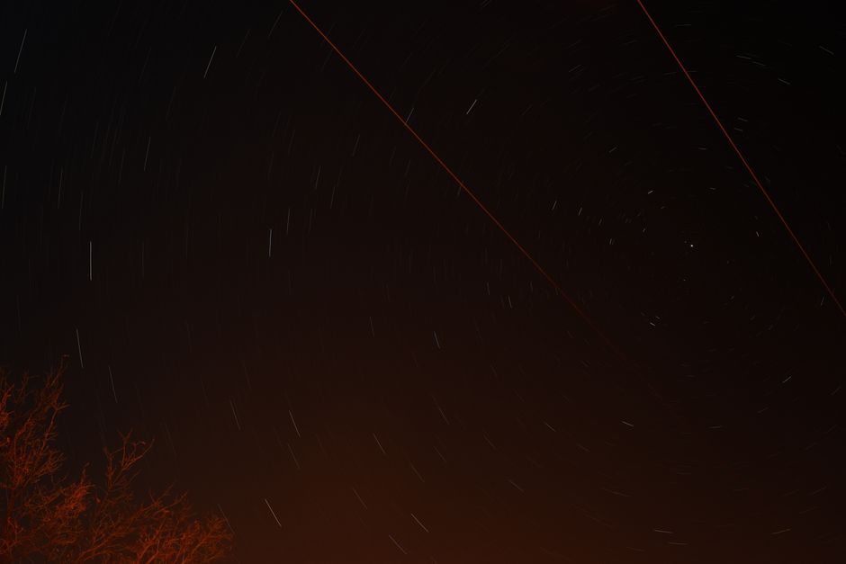 Captivating star trails over Ankara's night sky with red light streaks.