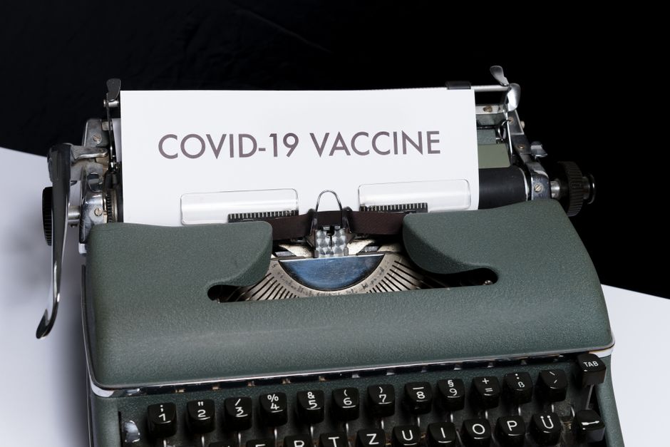 Close-up of a vintage typewriter with COVID-19 vaccine message on paper, conceptual health theme.