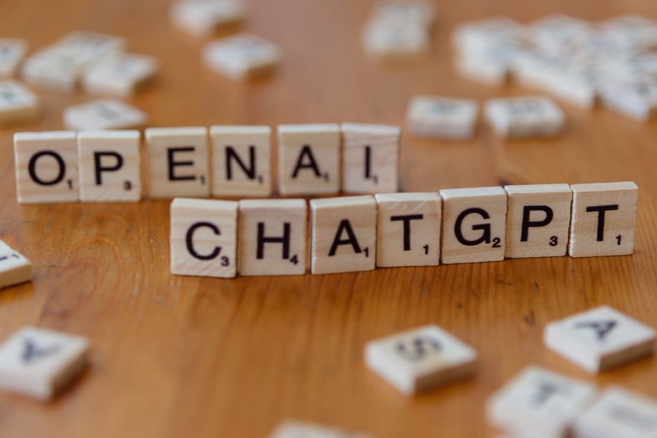 Wooden letter tiles spelling 'OPENAI CHATGPT' on a wooden surface, focused image.