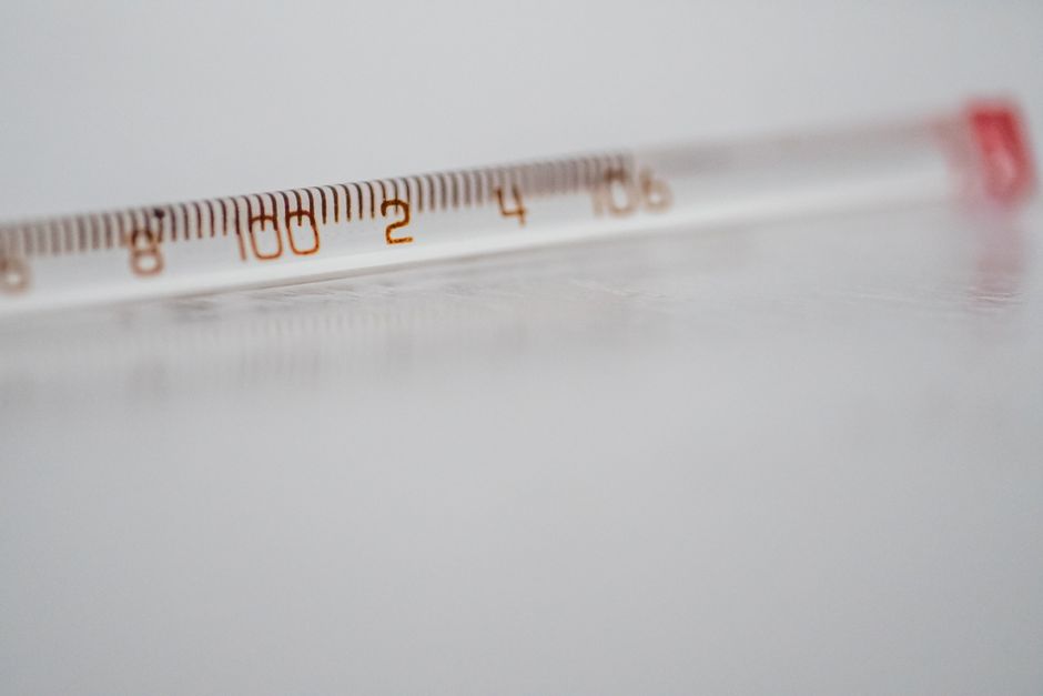Detailed close-up of a mercury glass thermometer on a white surface, showing temperature measurements.