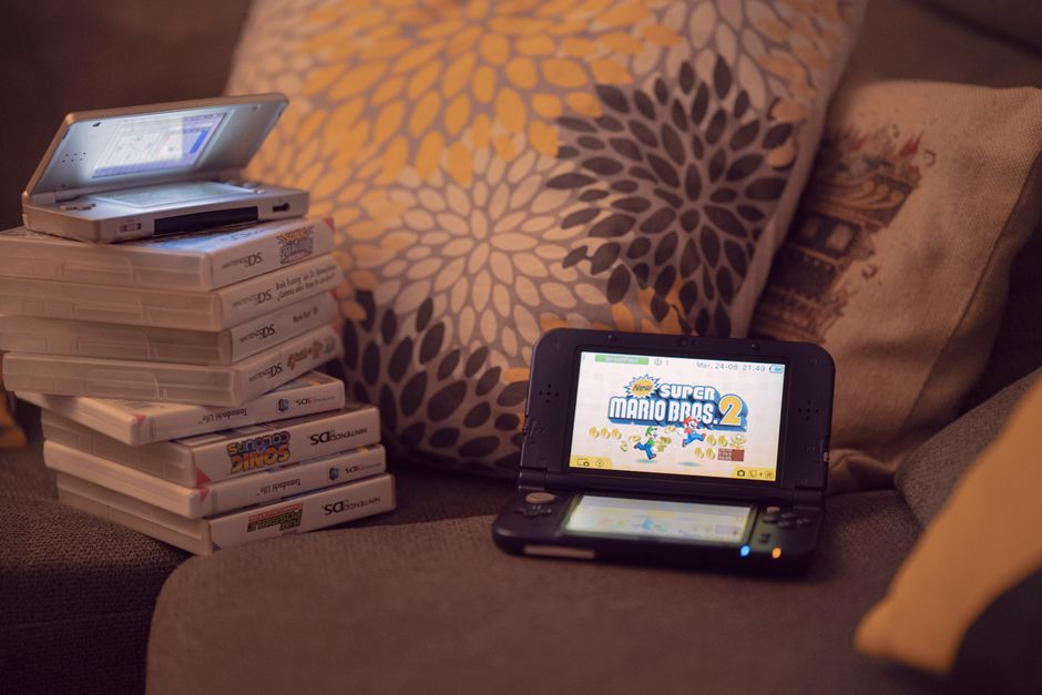 Two handheld gaming consoles on a sofa with game cartridges, creating a cozy game night mood.